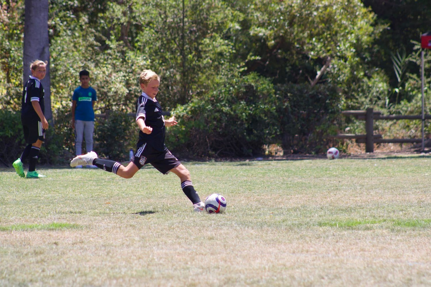 Boys player in black winding up to strike the ball