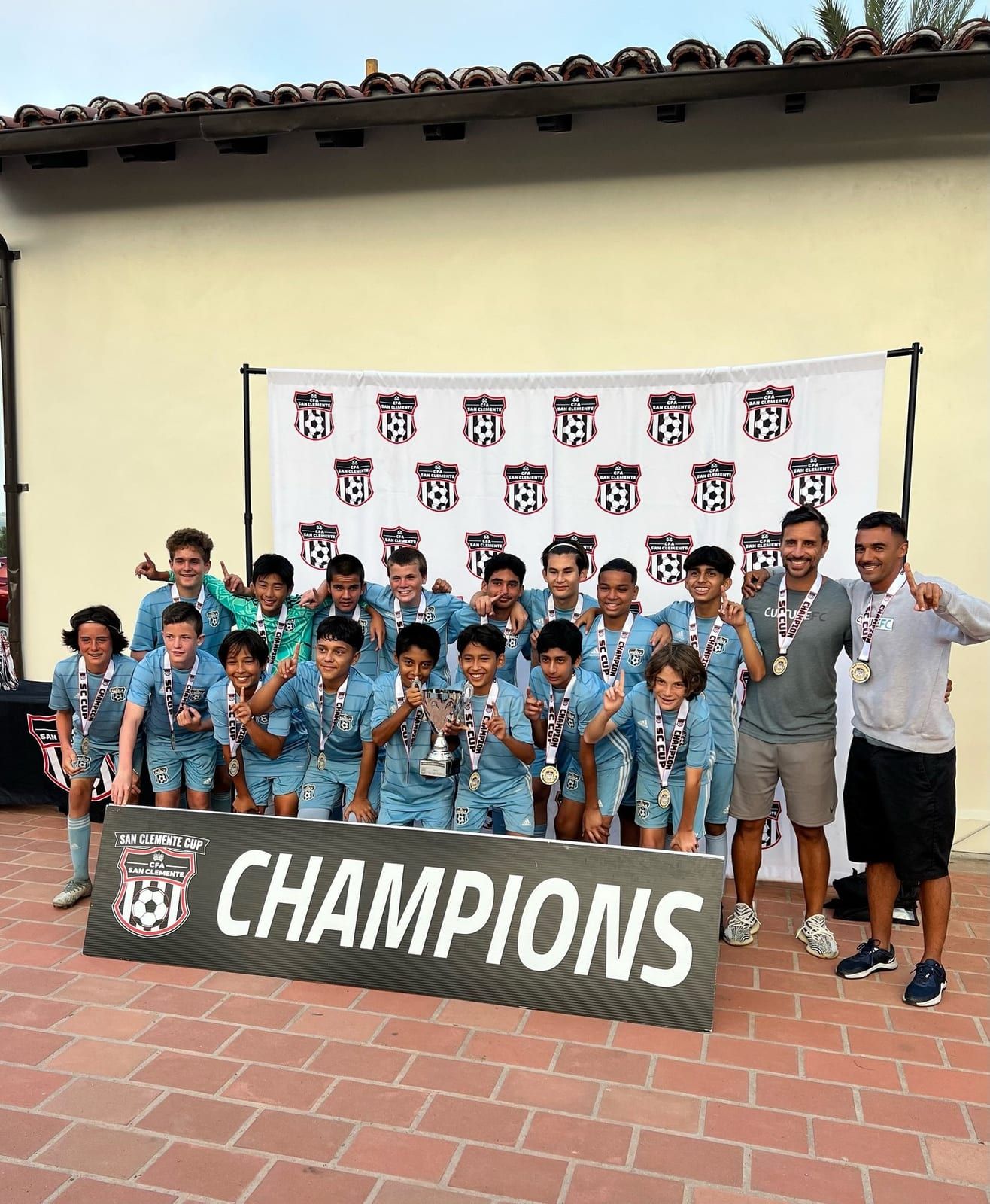 Boys champions with medals behind the San Clemente Cup champions banner
