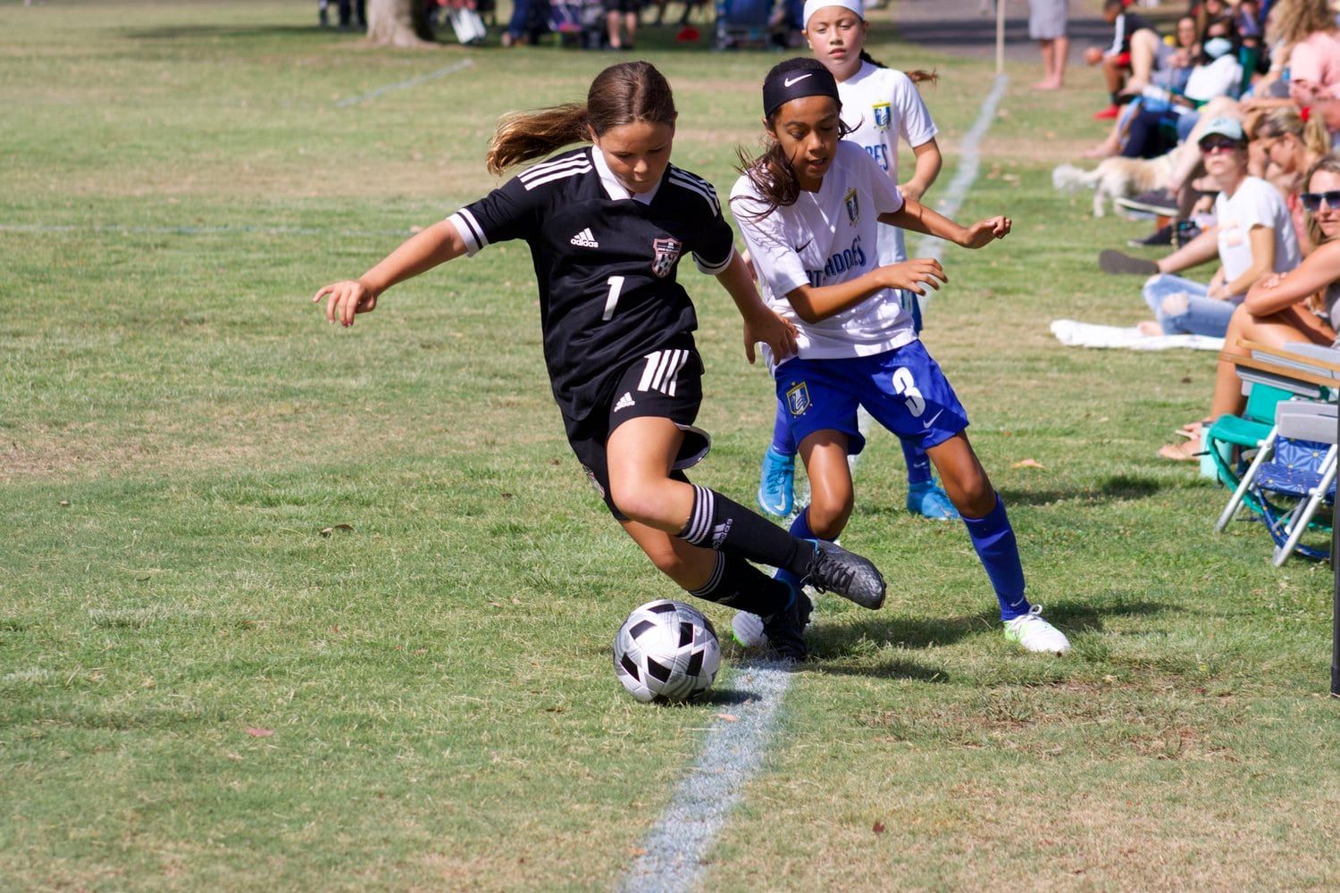 Girls player in black cutting past a defender at the San Clemente Cup