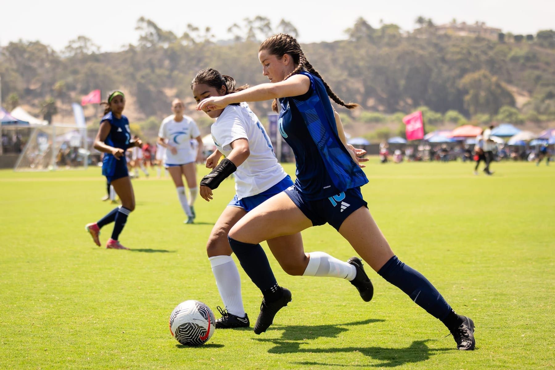 Girls player in navy driving past a defender at a tournament